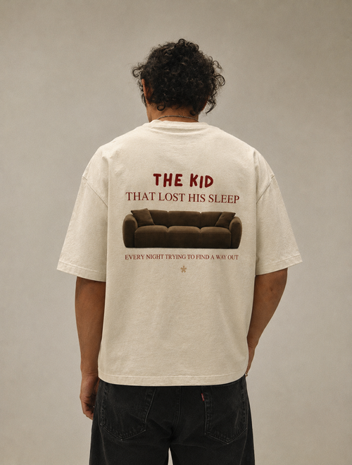 Person wearing a t-shirt with a graphic and text on the back, standing against a plain background